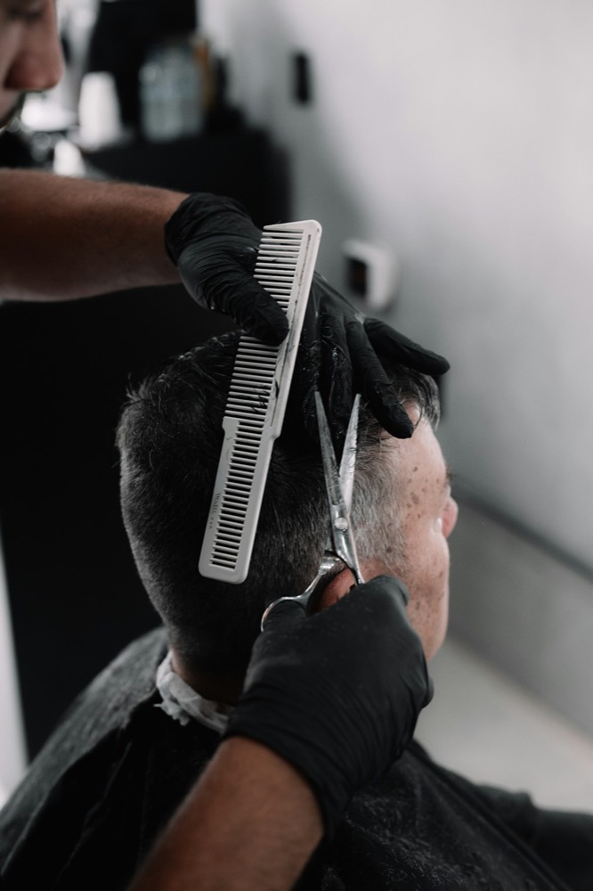 Barber shaping a cut with scissors and a comb